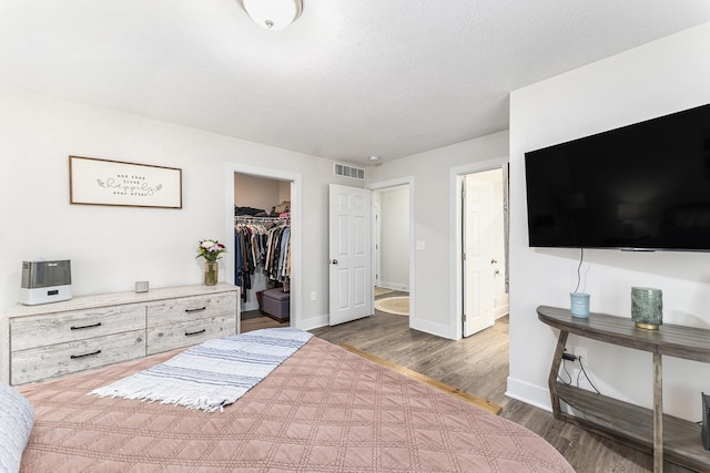 bedroom featuring wood finished floors, visible vents, a closet, and baseboards