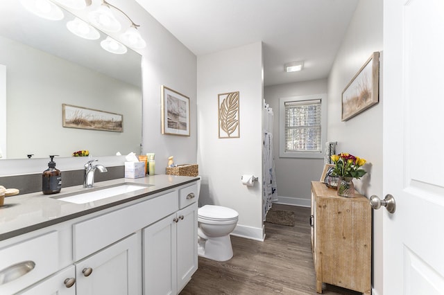 full bathroom with toilet, wood finished floors, a shower with shower curtain, baseboards, and vanity