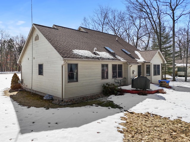 snow covered house with roof with shingles