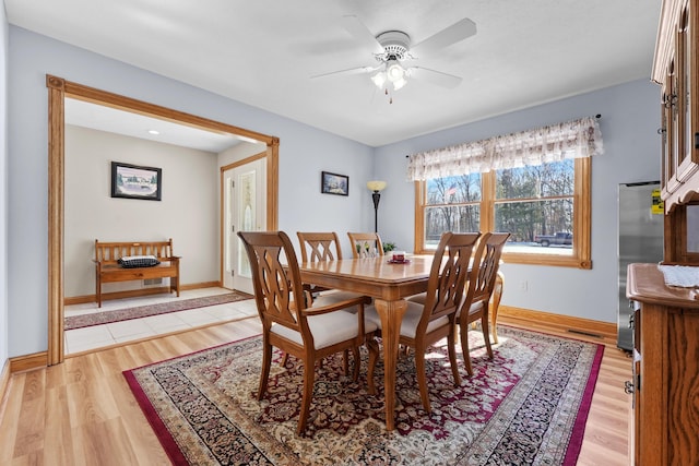 dining space featuring baseboards, a ceiling fan, and light wood finished floors