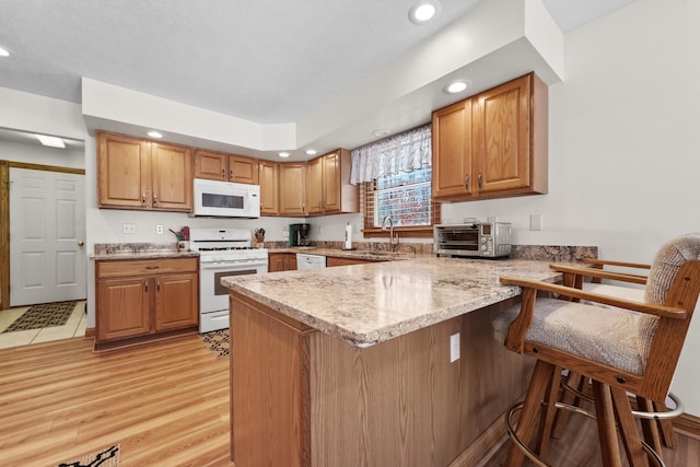 kitchen with white appliances, a peninsula, a toaster, a sink, and a kitchen bar