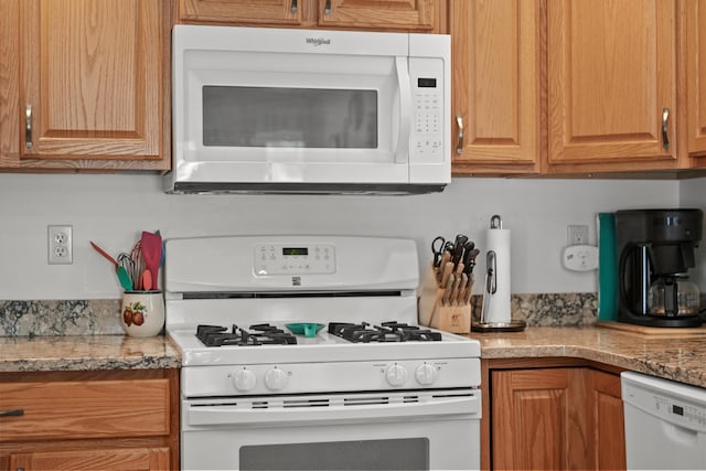 kitchen with white appliances and light stone countertops