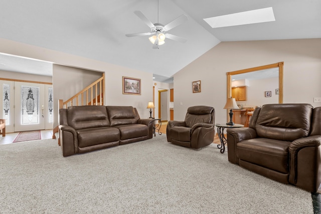 living room with stairs, lofted ceiling with skylight, a ceiling fan, and carpet floors