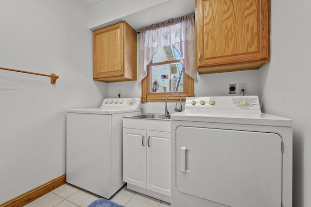 laundry room featuring baseboards, light tile patterned floors, washer and dryer, cabinet space, and a sink