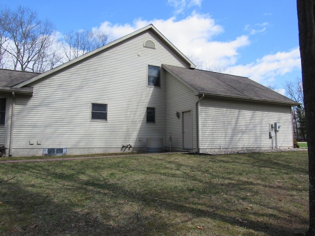 view of side of home with a shingled roof, cooling unit, and a yard