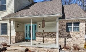 view of exterior entry featuring brick siding and roof with shingles