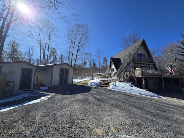 view of snow covered exterior featuring an outbuilding, a balcony, and a storage unit