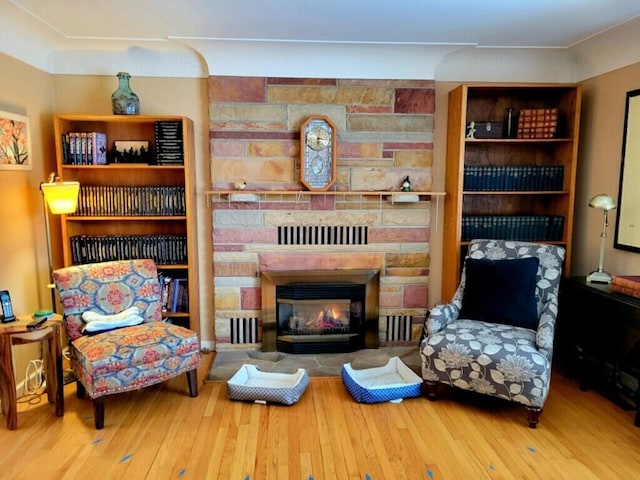 sitting room featuring a stone fireplace and hardwood / wood-style floors