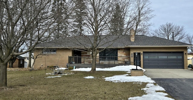 single story home featuring brick siding, a garage, driveway, and a chimney