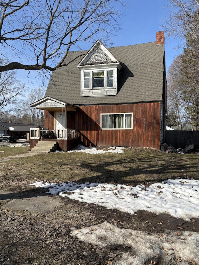 view of front of home with a chimney and a shingled roof