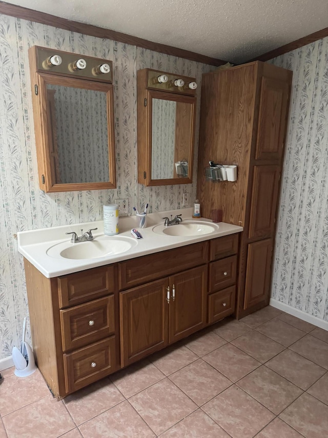 bathroom with a sink, a textured ceiling, double vanity, and wallpapered walls