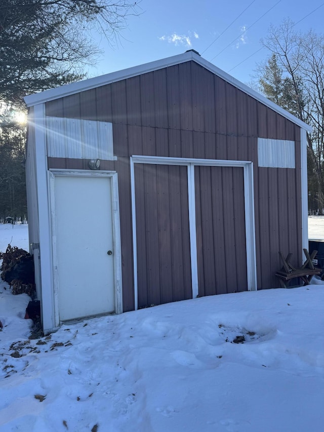 snow covered structure featuring an outbuilding