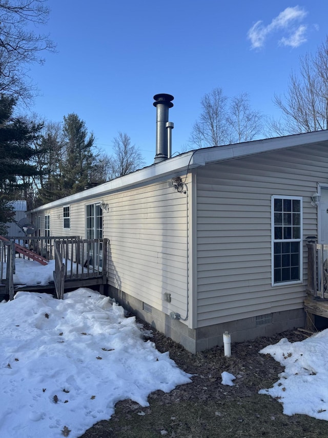 view of snow covered exterior with crawl space and a deck