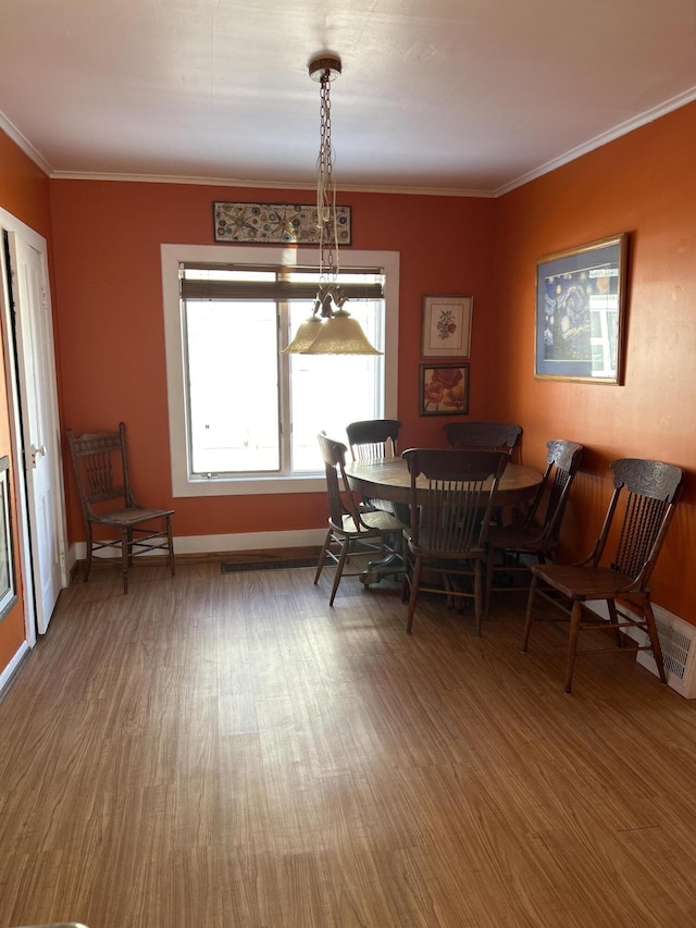 dining space featuring visible vents, crown molding, baseboards, and wood finished floors