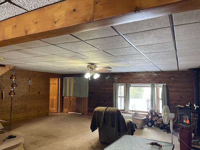 8610 Lincoln Bay Dr, Alpena, MI 49707 - carpeted living area with a wood stove, wood walls, and ceiling fan