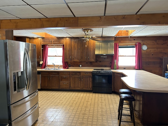 8610 Lincoln Bay Dr, Alpena, MI 49707 - kitchen with plenty of natural light, black / electric stove, a peninsula, wood walls, and stainless steel fridge with ice dispenser