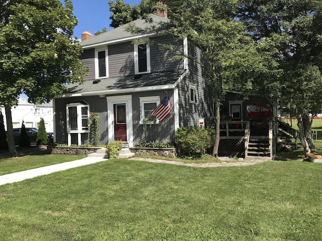 view of front facade with a deck, a front lawn, and a chimney