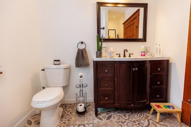 half bathroom featuring vanity, toilet, baseboards, and tile patterned flooring