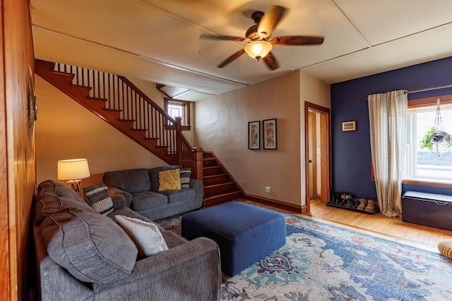 living room featuring ceiling fan, stairway, baseboards, and wood finished floors