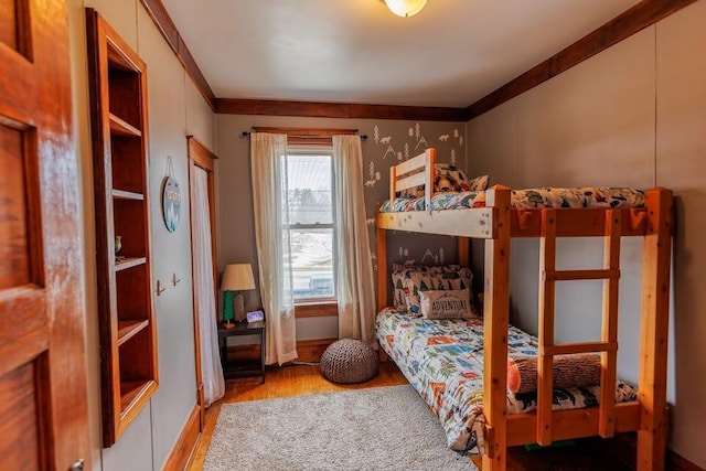 bedroom with wood finished floors and ornamental molding