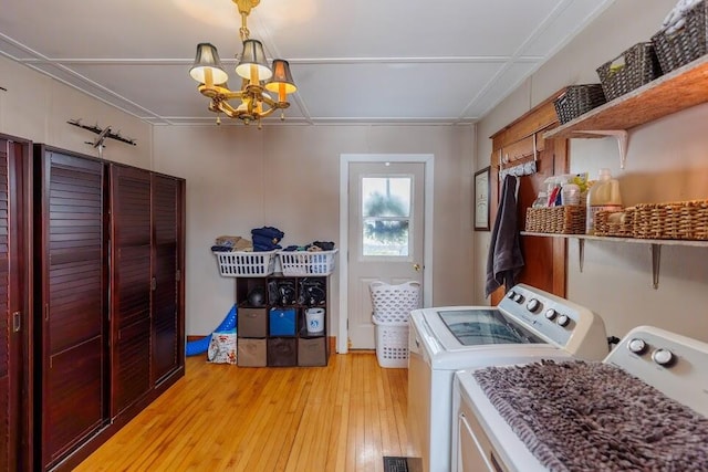 laundry room featuring washing machine and clothes dryer, laundry area, a chandelier, and light wood-style floors