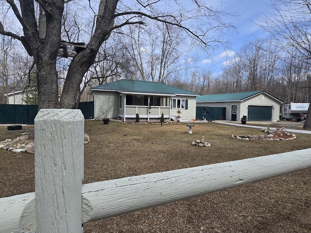view of front of home featuring a front lawn, fence, metal roof, and a garage