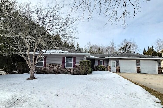 ranch-style house with stone siding, an attached garage, and driveway