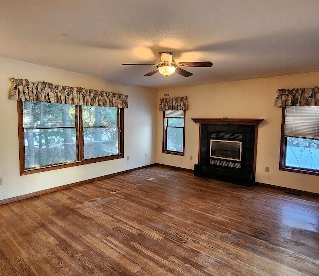 unfurnished living room with a glass covered fireplace, wood finished floors, and baseboards