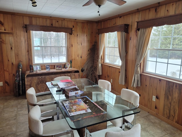 dining room featuring wooden walls, baseboards, and ceiling fan