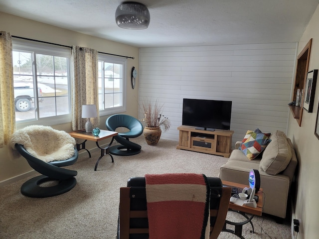 carpeted living room with baseboards, wooden walls, and a textured ceiling