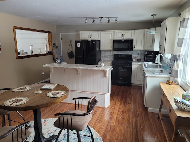 kitchen featuring dark wood-style floors, a kitchen island, a sink, black appliances, and tasteful backsplash