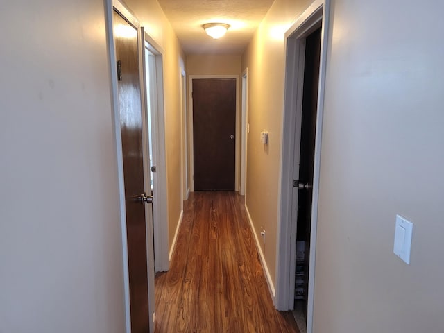 corridor featuring baseboards and wood finished floors