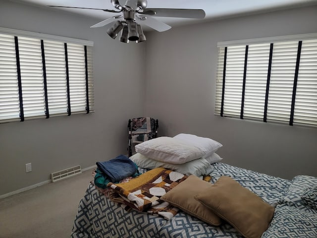 carpeted bedroom featuring visible vents, baseboards, and ceiling fan