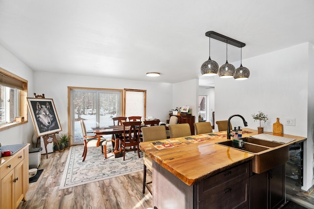 kitchen featuring wooden counters, a sink, light wood-style floors, pendant lighting, and a kitchen breakfast bar