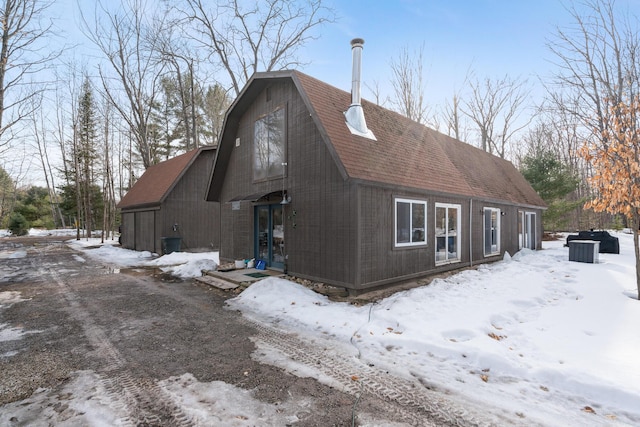 view of snow covered exterior featuring roof with shingles