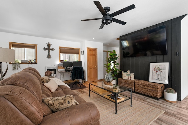 living room with heating unit, light wood finished floors, and ceiling fan