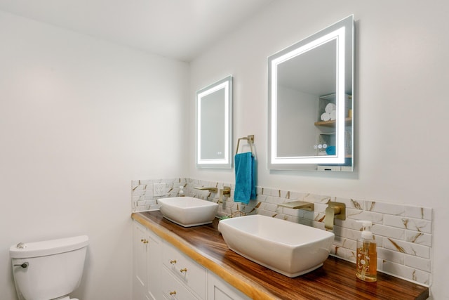 bathroom with a sink, decorative backsplash, toilet, and double vanity