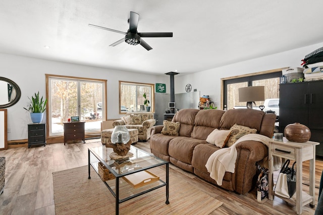 living area featuring a wood stove, wood finished floors, and ceiling fan