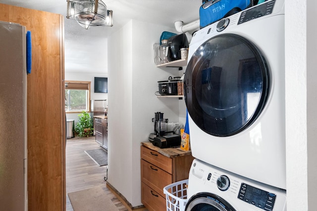 laundry room featuring light wood finished floors, laundry area, and stacked washing maching and dryer