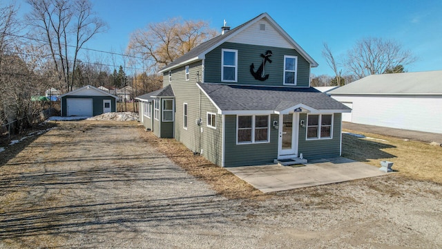 traditional home featuring a shingled roof, dirt driveway, entry steps, a garage, and an outbuilding