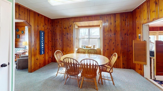 carpeted dining area with a wealth of natural light and wood walls