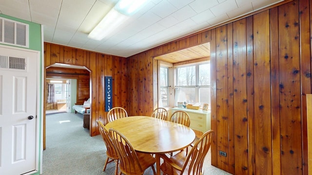 dining room with a wealth of natural light, arched walkways, and carpet