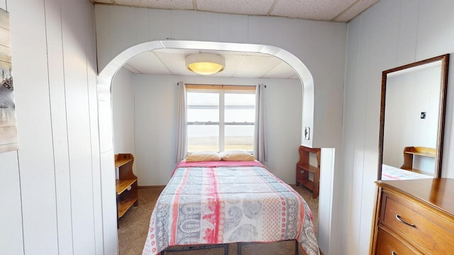 bedroom with a paneled ceiling, arched walkways, and carpet floors