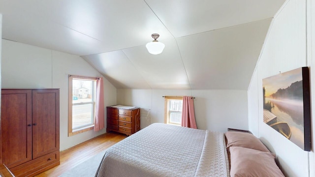 bedroom with light wood-type flooring, lofted ceiling, and multiple windows