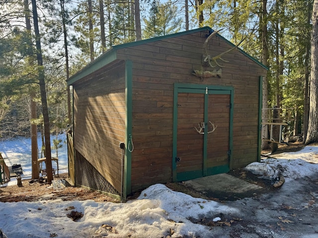 snow covered structure with an outdoor structure and a shed