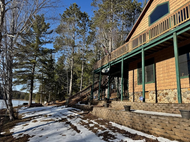 view of snow covered exterior with stairway and a deck