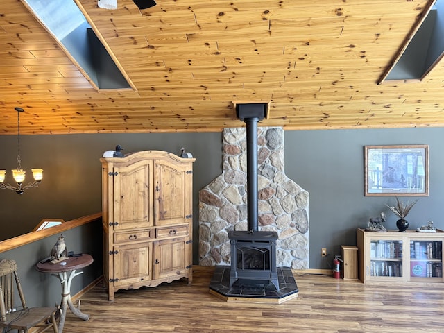 living room featuring a wood stove, baseboards, and wood finished floors