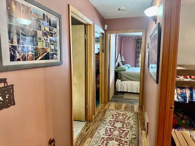 hall with a textured ceiling and wood finished floors