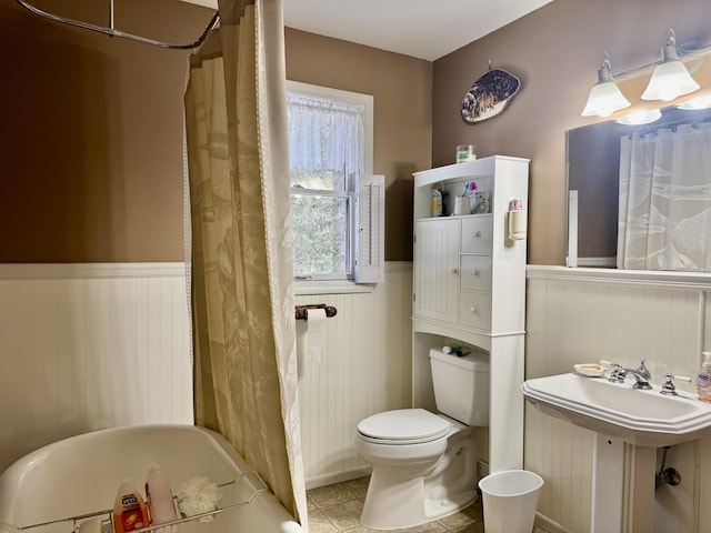 full bath with a shower with curtain, toilet, wainscoting, tile patterned flooring, and a bathtub