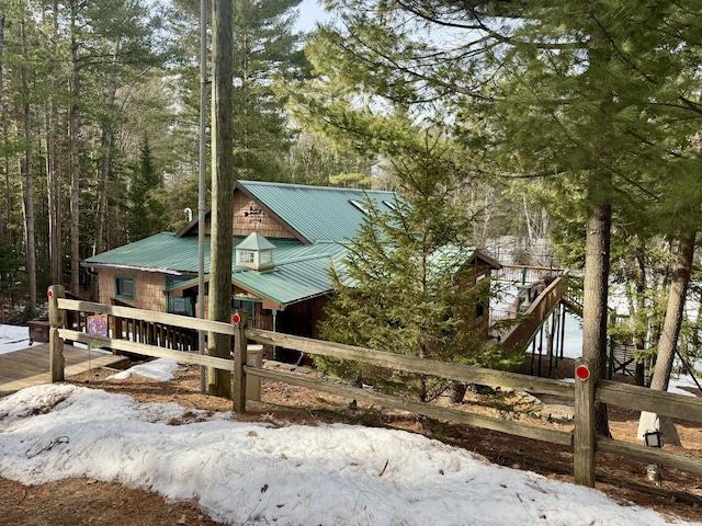 view of front of home featuring metal roof and fence